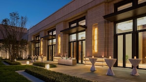 A modern building exterior with large windows, a well-lit outdoor seating area, and neatly arranged tables. - Hyatt Regency Xi An (Xi'an)