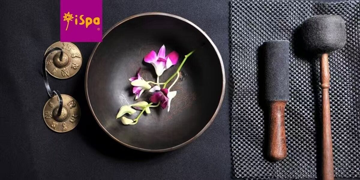 A dark bowl with flowers and two metallic objects on a black surface.