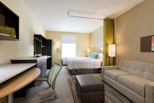 Habitación de hotel con escritorio, silla, cama, sofá y televisor.