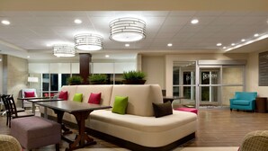 A modern lobby with a seating area, a reception desk, and a glass door entrance.