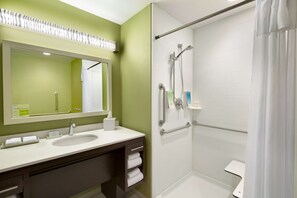Een badkamer met een wastafel, spiegel en douche.