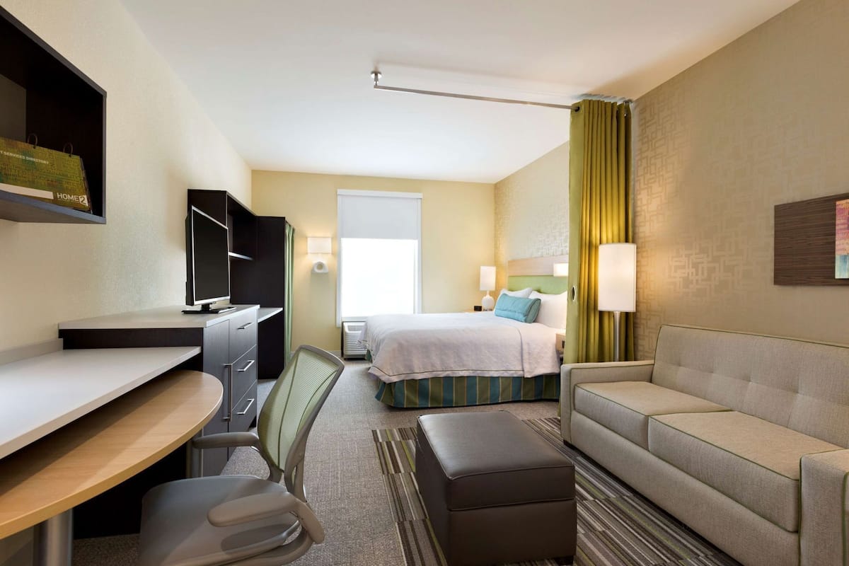 Habitación de hotel con escritorio, silla, cama y sofá.