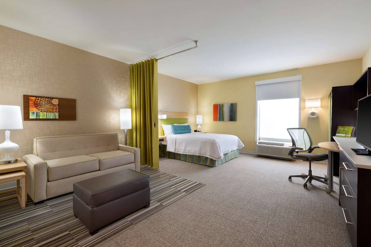 Una habitación de hotel con sofá, cama, escritorio, silla y televisor.