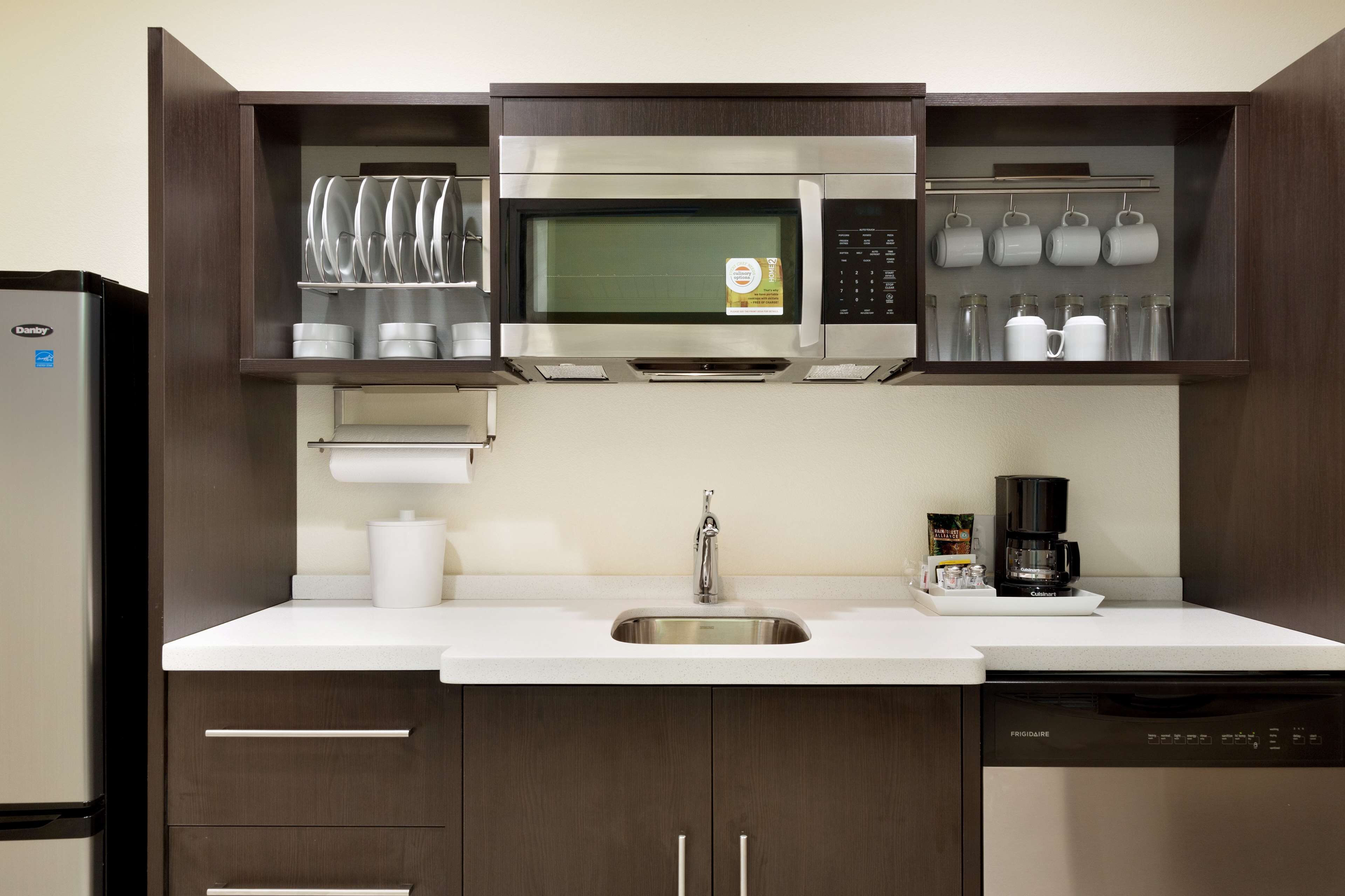 A compact kitchen with a built-in microwave, a coffee maker, and a dishwasher.