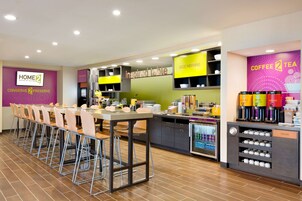Uma cozinha de hotel moderna com uma longa mesa de jantar, banquetas de bar e um espaço para café.