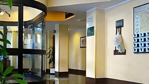 A hotel lobby with a glass partition, a map on the wall, and a plant. - Residence Desenzano (Milan)