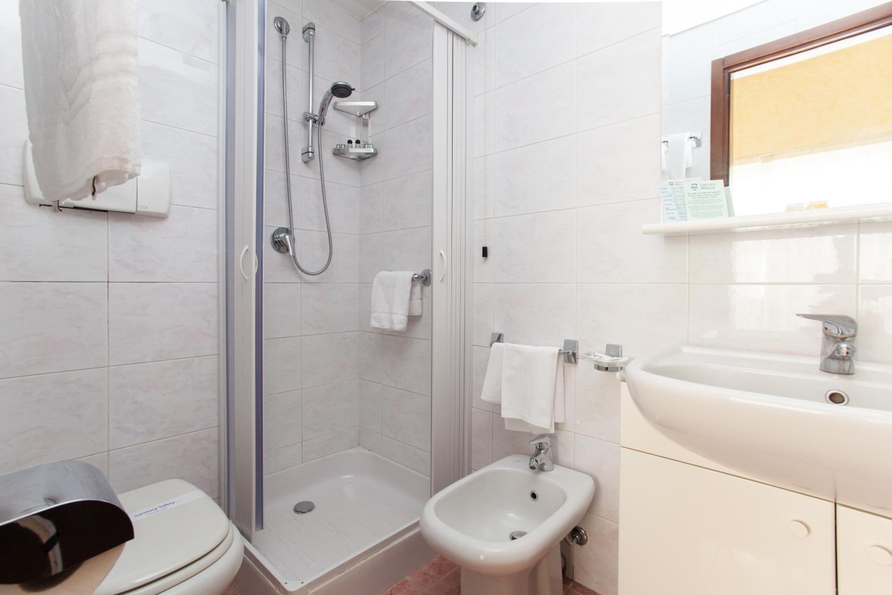 A bathroom with a shower, toilet, bidet, and sink.