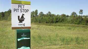 A sign for a pet pit stop with a toilet symbol and a green box labeled "Poopy Pouch".