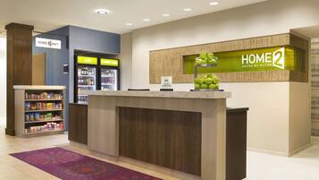 A hotel reception area with a counter, a refrigerator, and a snack bar.