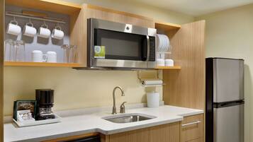 A modern kitchen with a stainless steel microwave, a coffee maker, a sink, and a refrigerator.
