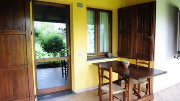 Una mesa de comedor de madera con sillas, una ventana con cortinas y una puerta que da a un área exterior.