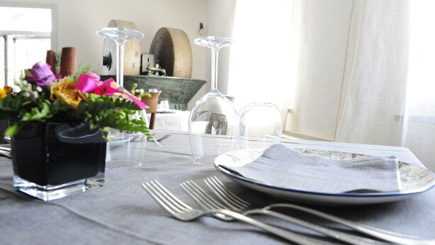 A dining table set with a vase of flowers, wine glasses, and cutlery. - Sa Mola (Bonarcado)