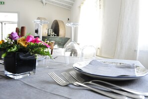 A dining table set with a vase of flowers, wine glasses, and cutlery. - Sa Mola (Bonarcado)