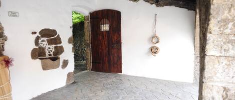 A stone-paved courtyard with a wooden door and a stone wall with a sign reading "Sala Giere".