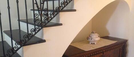 A staircase with ornate black metal railings and a wooden chest at the bottom.