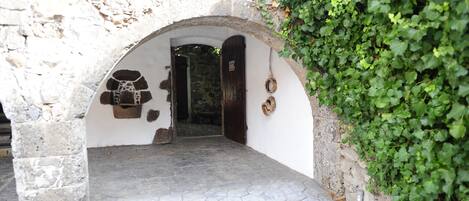 An arched stone doorway leading into a building, with a stone floor and a wall covered in green ivy.