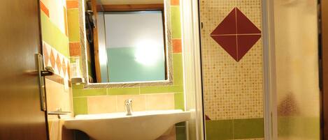 A bathroom with a sink, mirror, shower, and toilet.