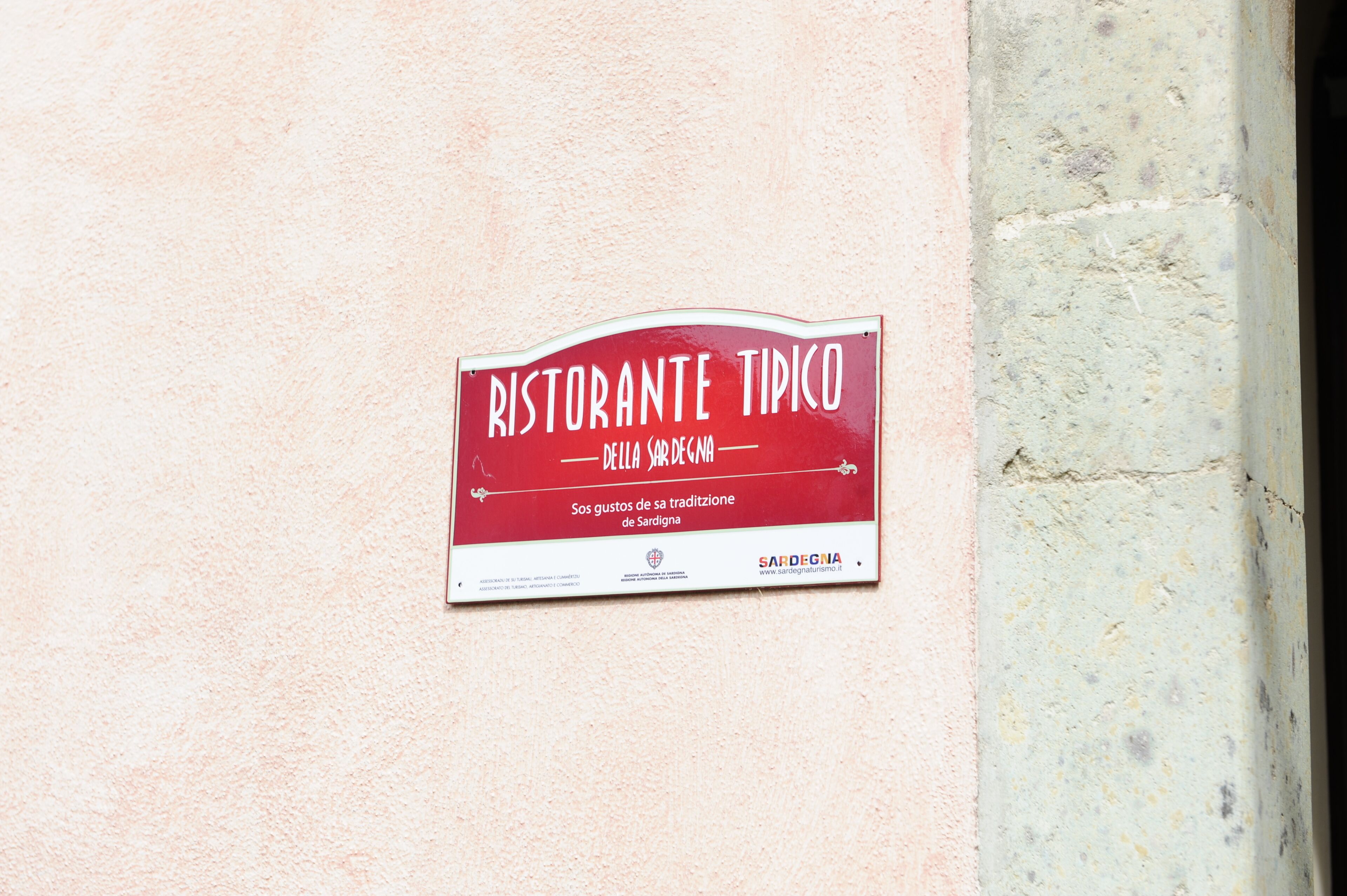 Un letrero que dice 'RISTORANTE TIPICO DELLA SARDEGNA' en una pared.