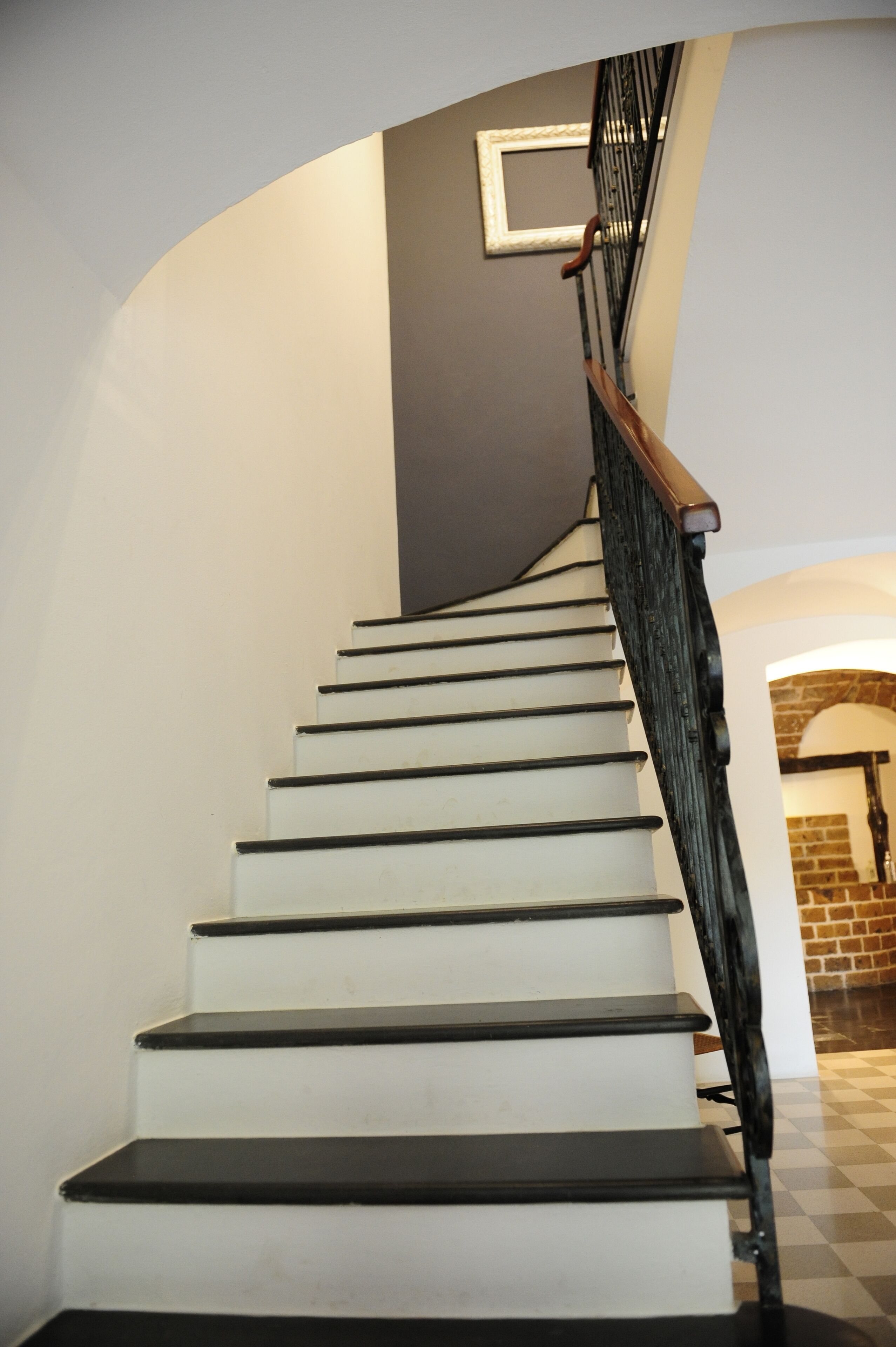 A staircase with white steps and a black handrail, leading to a landing with a framed picture.