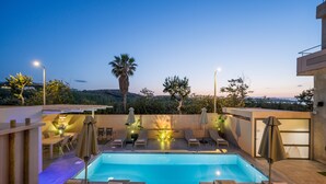 A rooftop pool area with lounge chairs, umbrellas, and a view of the surrounding landscape. - Sea & City Apartments (Chania)