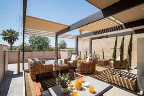 An outdoor patio with wicker furniture, a table with drinks, and a view of the landscape. - Sea & City Apartments (Chania)