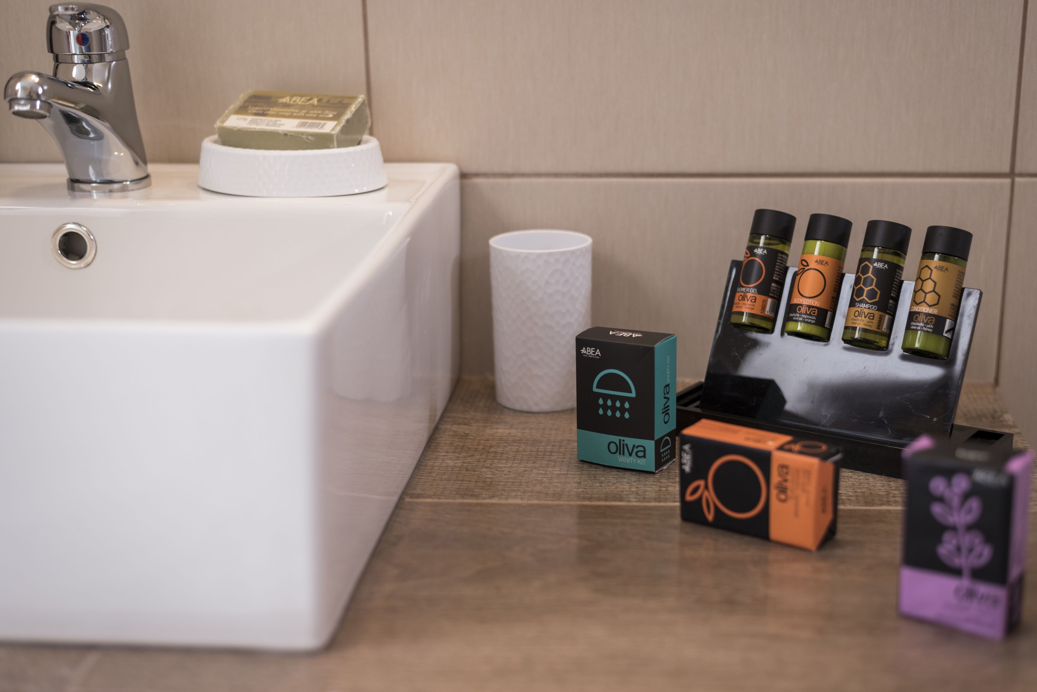 A bathroom sink with toiletries and a box of olive oil.