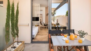 A modern hotel room with a balcony, a dining area with orange juice, and a TV in the background. - Sea & City Apartments (Chania)