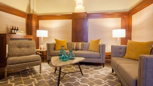 A cozy living room with patterned furniture, a coffee table with decorative vases, and two lamps on side tables. - Hotel 32One (San Francisco)