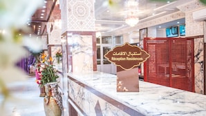 A reception desk with a marble countertop, a sign indicating 'Reception Residences', and a red partition in the background.