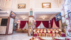A luxurious lobby with a marble floor, a plush sofa set, and a large vase with flowers.