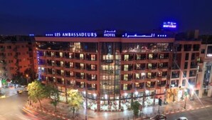 A multi-story hotel with a prominent sign reading "LES AMBASSADEURS HOTEL".