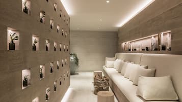A modern interior with a long, narrow hallway, a sofa with cushions, and a wall with multiple small windows.