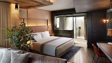 A modern hotel room with a large bed, a desk, and a seating area.