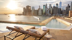 Una piscina en la azotea con sillones de descanso y vistas a la ciudad.