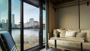 Una sala de estar moderna con un amplio ventanal que da a una vista panorámica de la ciudad y un río.