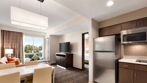 A modern hotel room with a dining area, a flat-screen TV, a refrigerator, and a microwave. - Homewood Suites By Hilton Irvine John Wayne Airport (Irvine)