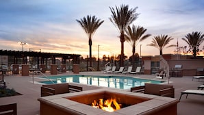 A poolside area with lounge chairs, a fire pit, and palm trees. - Homewood Suites By Hilton Irvine John Wayne Airport (Irvine)