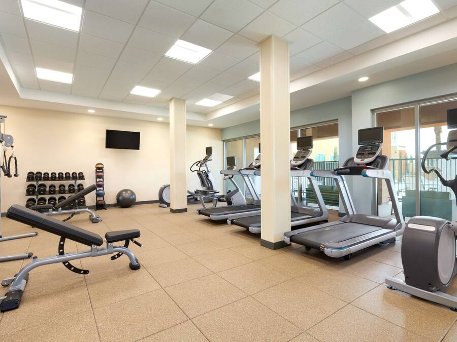 A gym with treadmills, elliptical machines, and free weights.