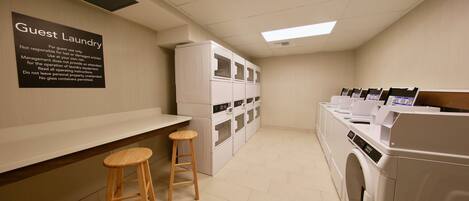 A guest laundry area with multiple washing machines, a bench, and a sign detailing usage instructions.