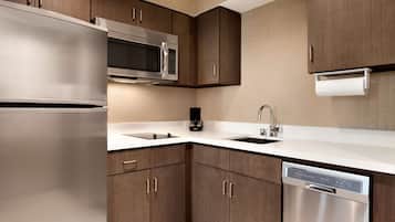 A modern kitchen with stainless steel appliances, wooden cabinets, and a white countertop.
