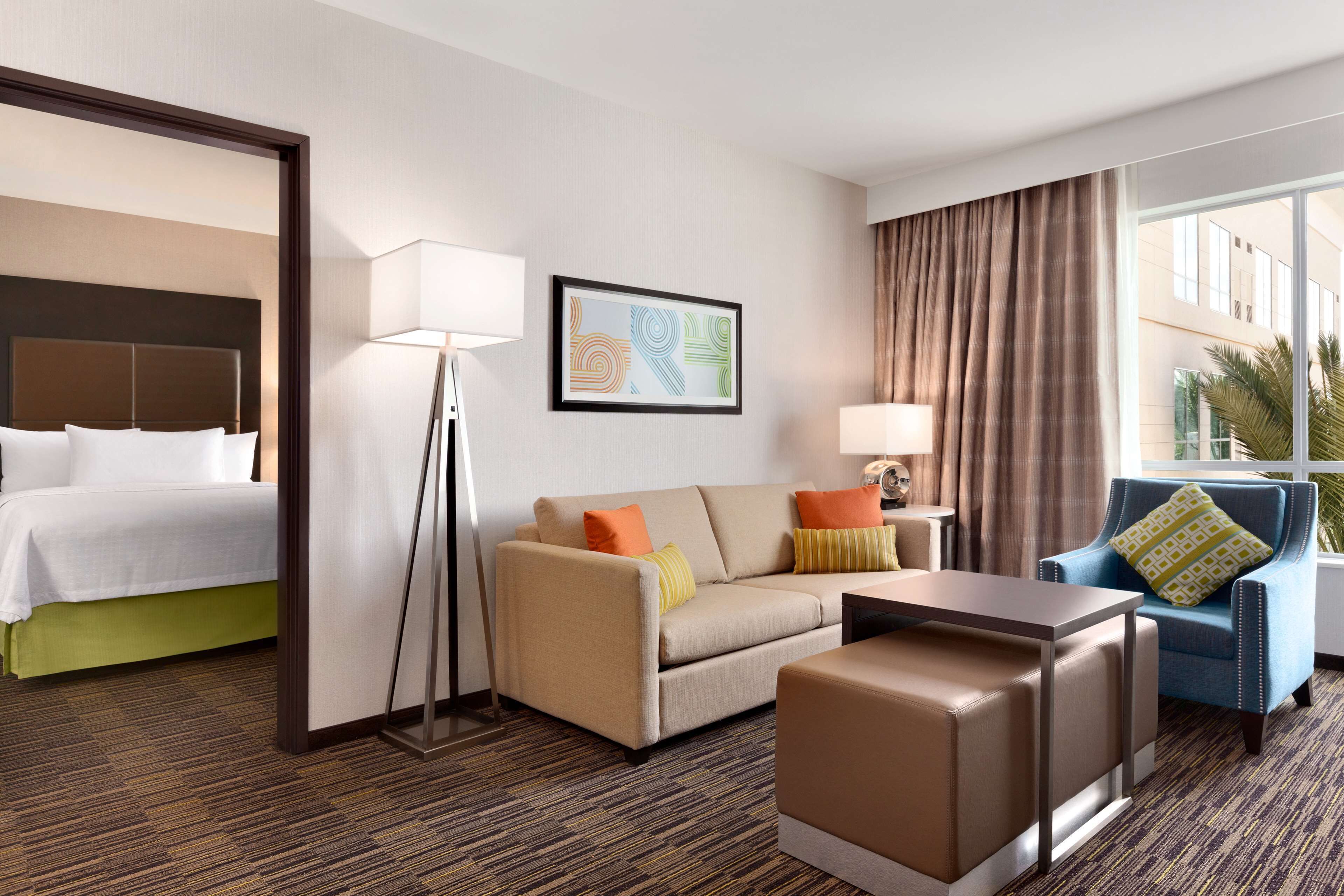 Ein Hotelzimmer mit Bett, Sofa, Couchtisch, Sessel und Lampe.