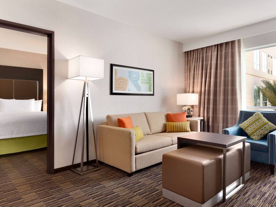 Ein Hotelzimmer mit Bett, Sofa, Couchtisch, Sessel und Lampe.