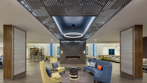A spacious lobby with a modern ceiling design, a central fireplace, and comfortable seating areas. - Homewood Suites By Hilton Irvine John Wayne Airport (Irvine)