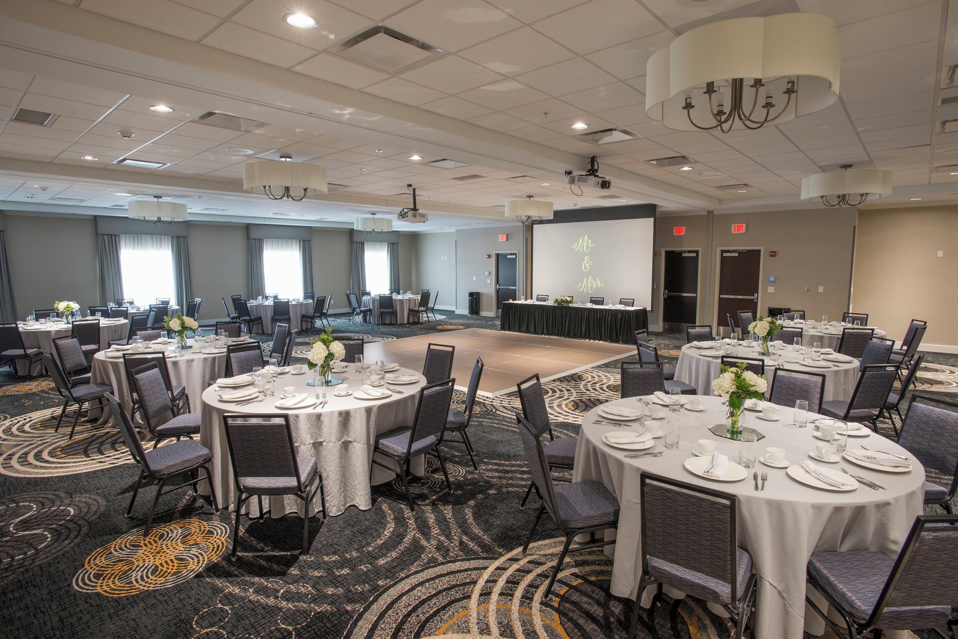 A conference room with multiple tables set for a meeting, equipped with projectors and screens.