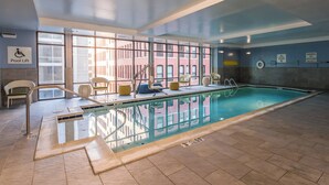 An indoor swimming pool with clear glass walls, a pool lift, and a lifeguard station. - voco The Clair Cincinnati Downtown by IHG (Cincinnati)