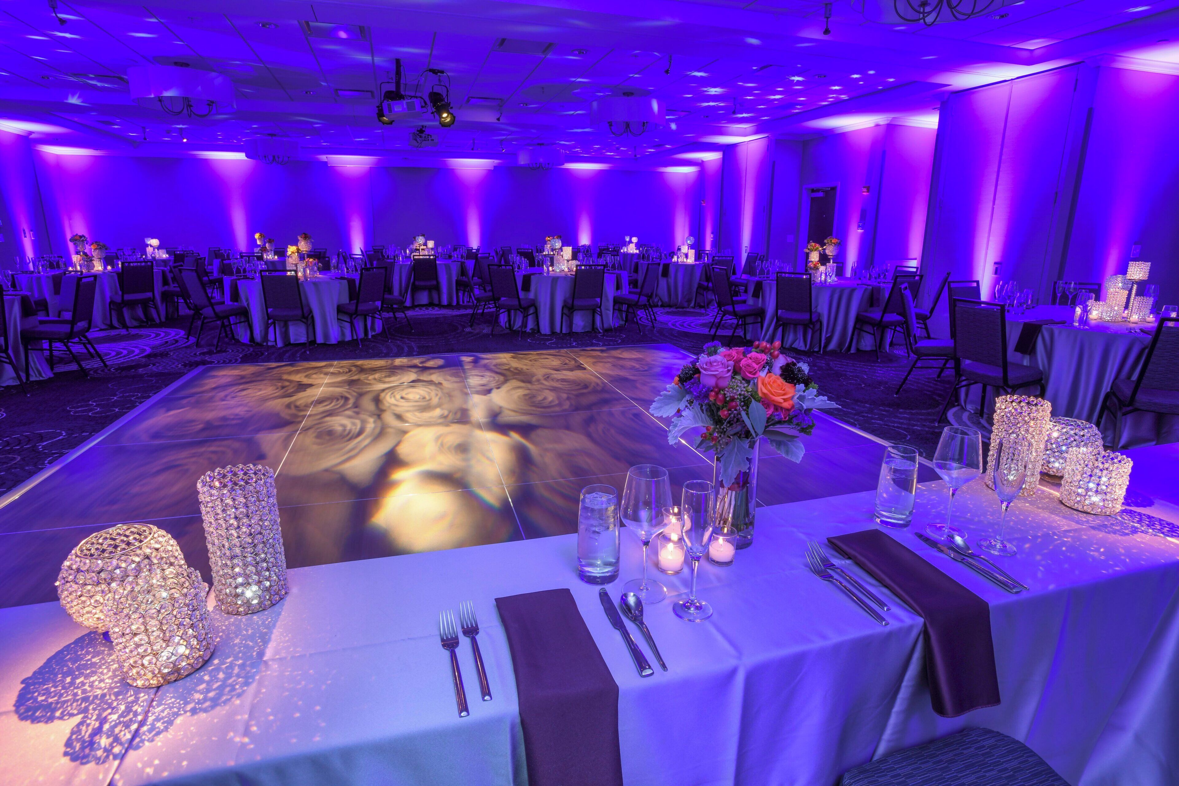 A banquet hall with round tables, chairs, and a central dance floor.
