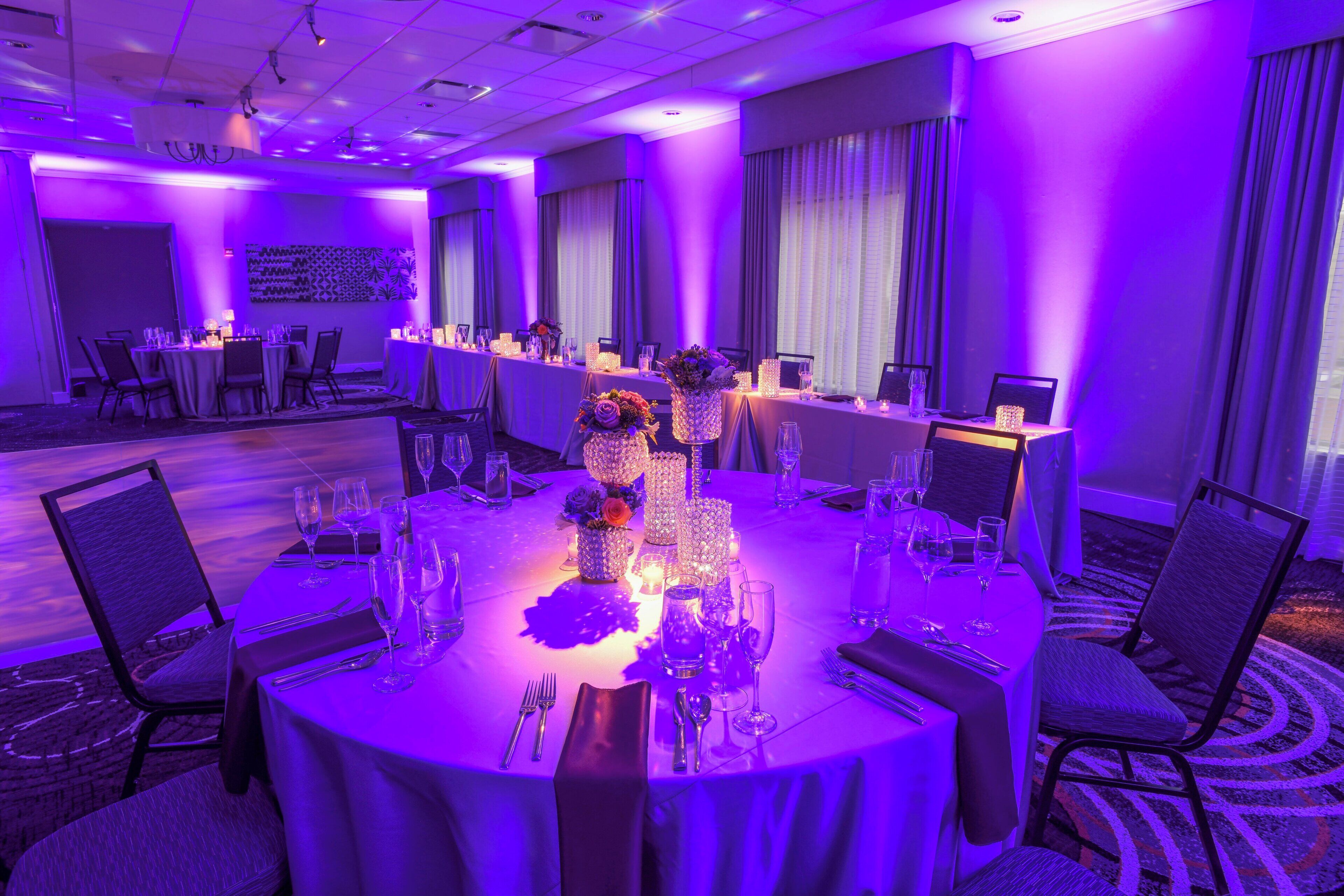 A hotel dining area with round tables, chairs, and a buffet setup.