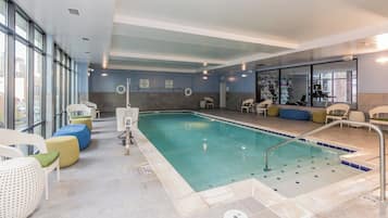Una piscina interior con agua cristalina, rodeada de zonas de estar con distintos colores.