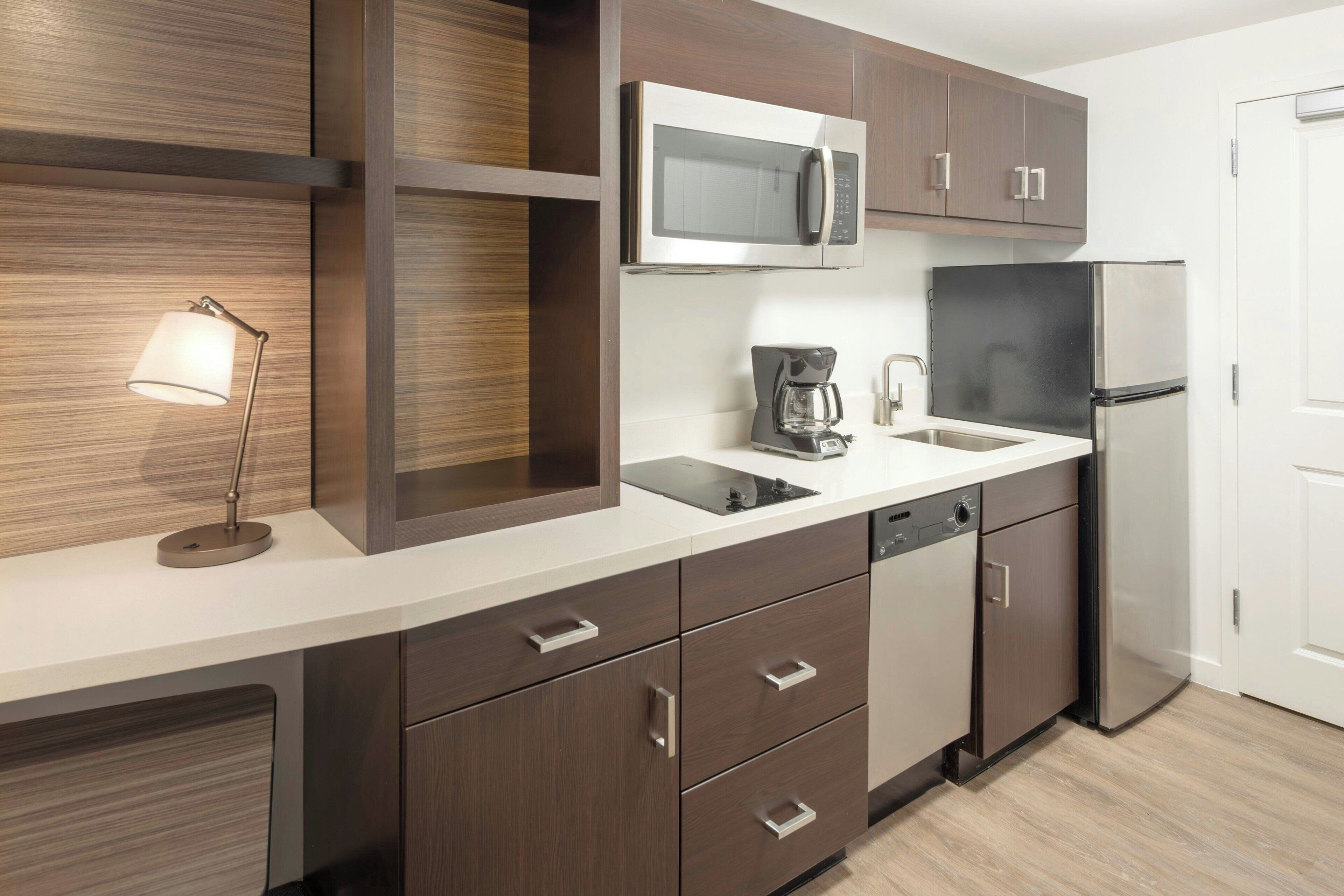 Una cocina moderna con armarios de madera oscura, un refrigerador de acero inoxidable, un microondas y una cafetera.