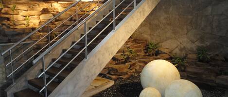 Una escalera con barandillas de metal que conduce a un muro de piedra.